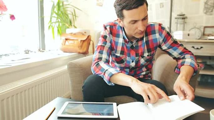 男性学习或使用书籍和数字平板电脑进行研究。