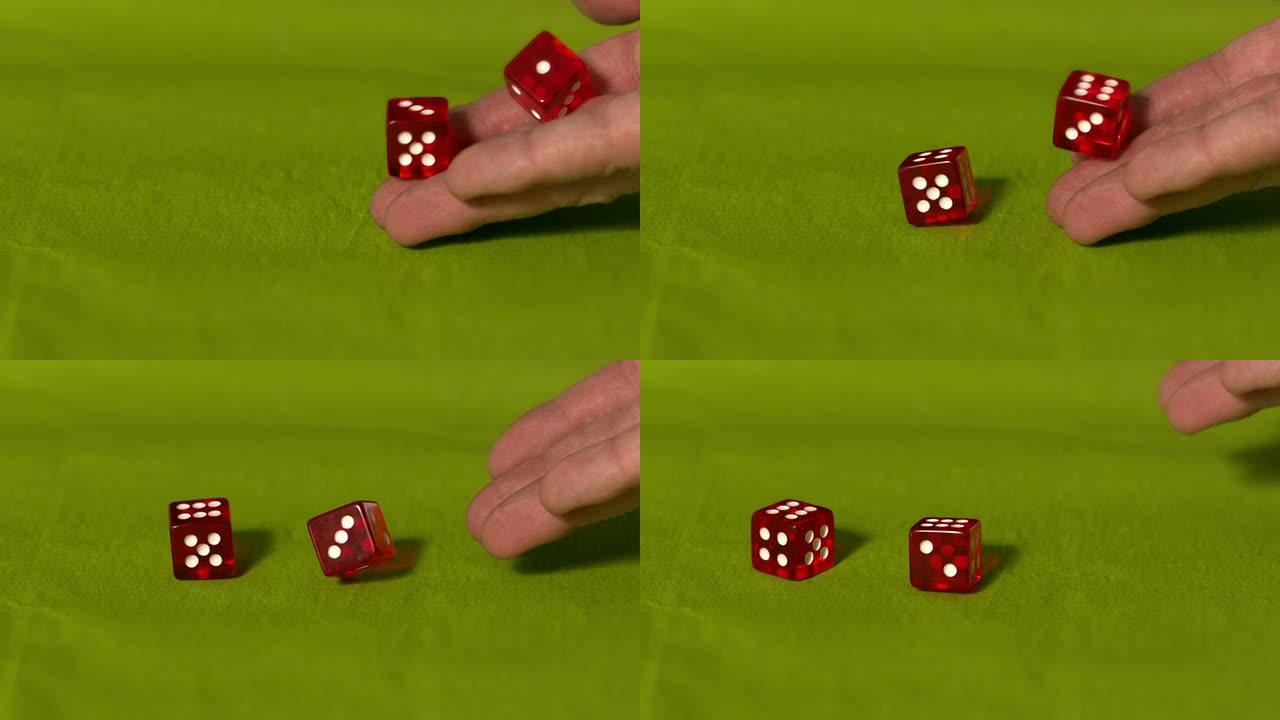 手在绿色桌子上滚动两个红色骰子
