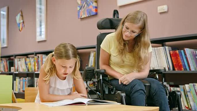 坐在轮椅上的DS女人在图书馆里听一个女孩读书