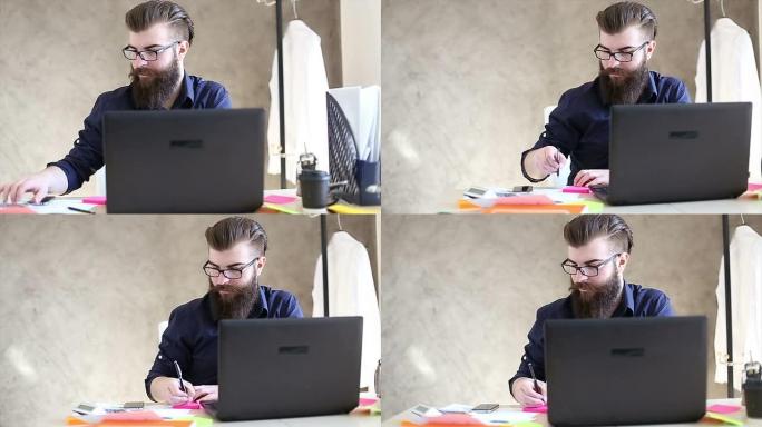 英俊的时髦胡子男子在办公室里用电脑工作