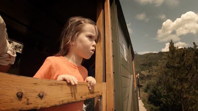 火车上的孩子-一个小女孩喜欢乘火车的第一次旅行。窗外的山景。