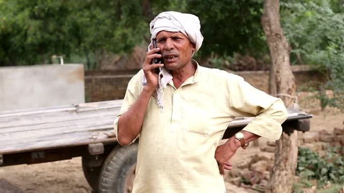 男人在手机上聊天沟通讲话农村户外拖拉机