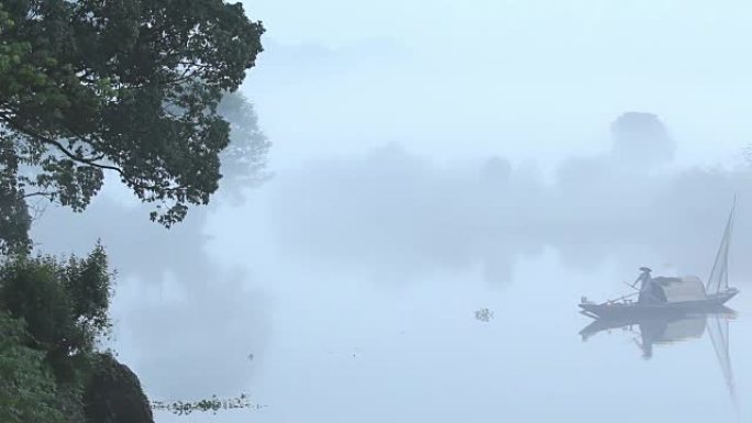 雾天宁静湖水上的小渔船