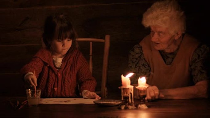 一个年轻的女孩在烛光下与祖母一起绘画