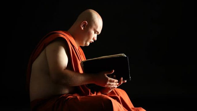 佛教僧侣在黑暗中阅读圣书