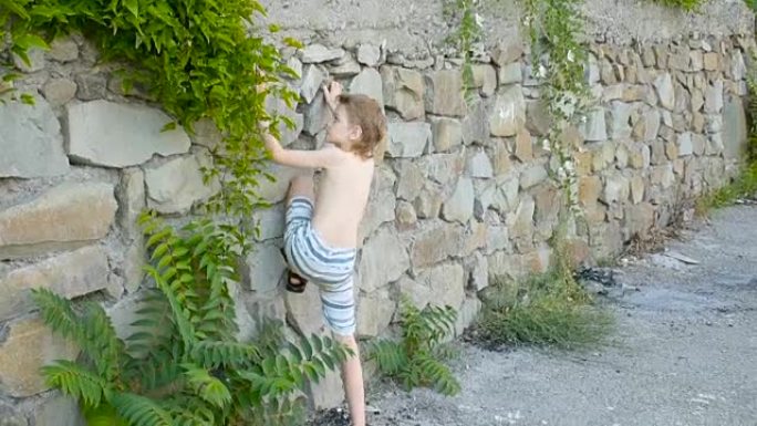 男孩爬上石头挡土墙