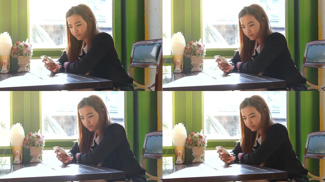 亚洲女子在咖啡馆喝咖啡时使用智能手机触摸屏