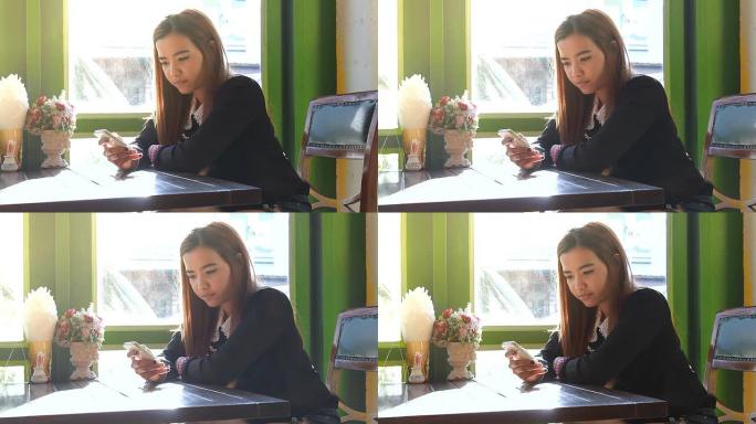 亚洲女子在咖啡馆喝咖啡时使用智能手机触摸屏