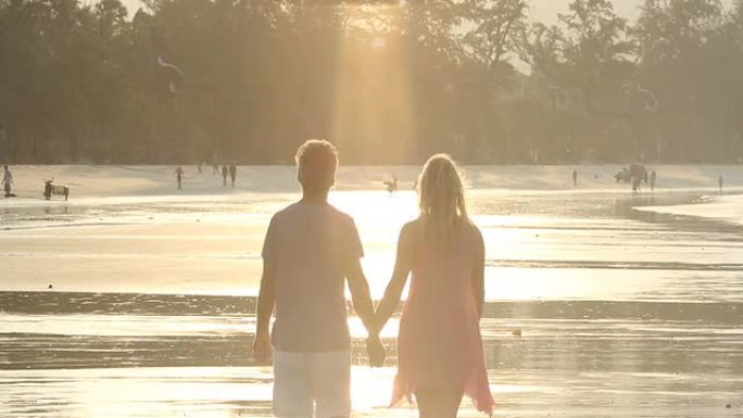 日出时，情侣们沿着海滩、滩涂散步