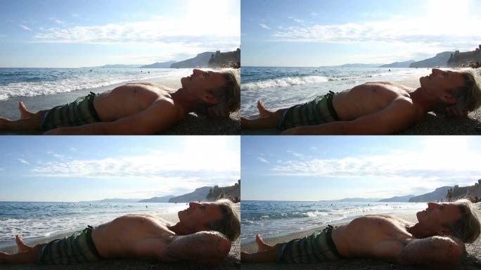 男子在平缓的海浪中在海滩上放松