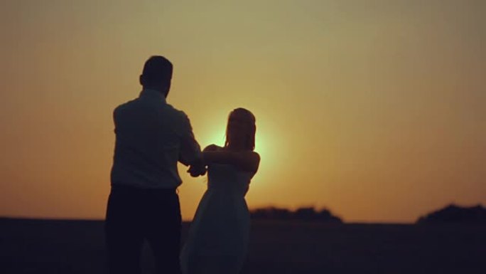 日落时分，浪漫的情侣在草地上跳舞