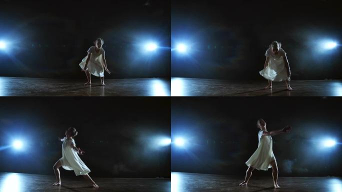 一名年轻的女芭蕾舞演员赤脚跳上舞台，穿着宽松的白色连衣裙慢动作