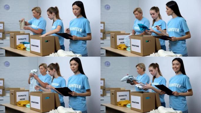 志愿者将衣服放在捐款箱中，微笑的社工做笔记