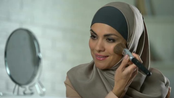 自信的阿拉伯女士化妆，用刷子涂抹粉末，女性气质