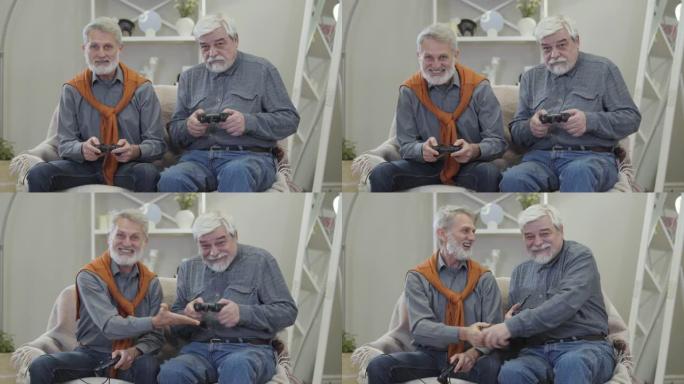 两个快乐的白人老人玩电子游戏，给了五个，微笑着。积极开朗的退休人员在室内玩得开心。
