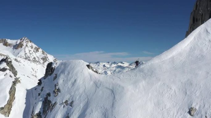男性登山者登上陡峭的积雪覆盖的山脉的空中无人机视图