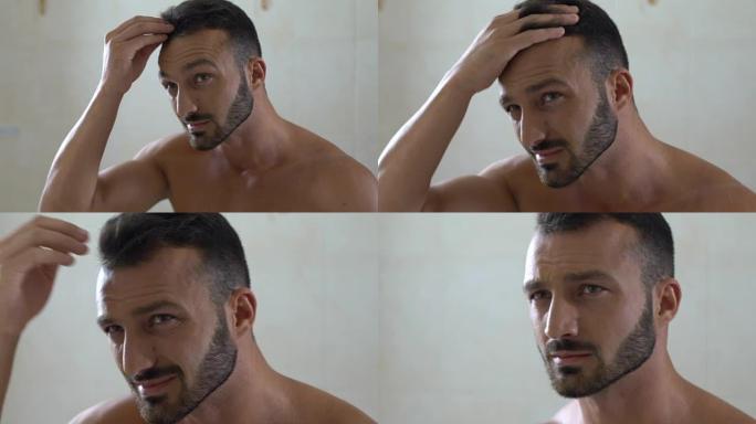 不快乐的男人在浴室的镜子前检查易碎的头发，头皮屑