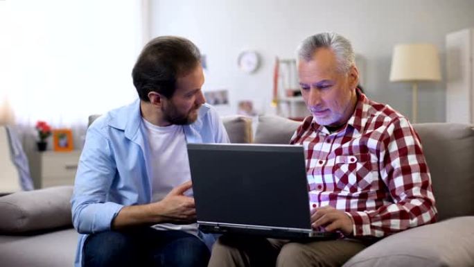 年幼的儿子向年迈的父亲解释如何使用笔记本电脑，现代技术，设备