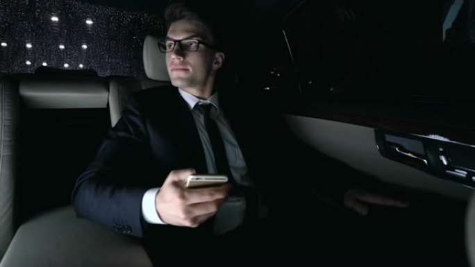 穿着西装的男性在开车回家时与女友在汽车后座上发短信，调情
