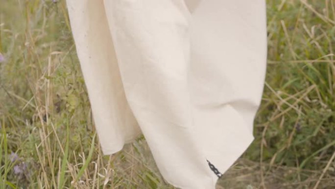 光着脚的女人在白色长裙走过田野特写。