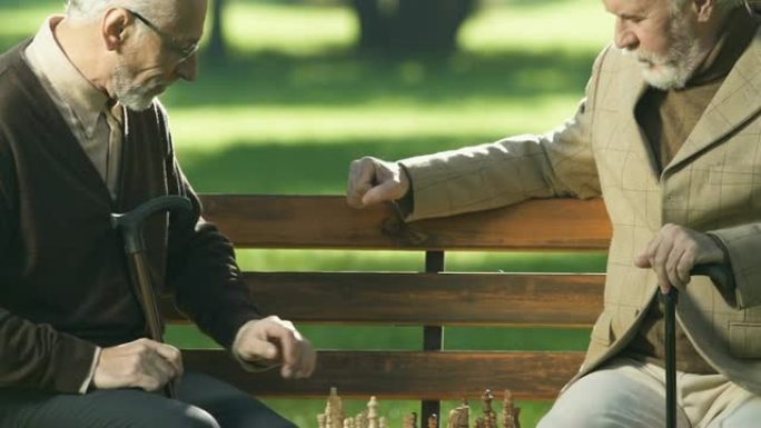 退休男性朋友在板凳上下棋，一起玩乐，将死