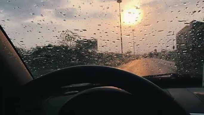 日落时，用雨滴在汽车挡风玻璃上向前行驶