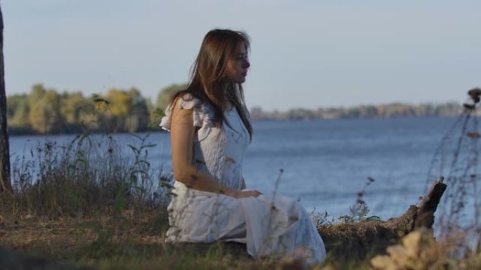 神秘的高加索女人坐在湖岸上环顾四周