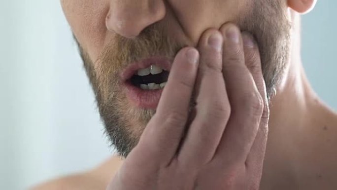 男子触摸脸颊感到浴室牙痛，龋齿，牙髓发炎