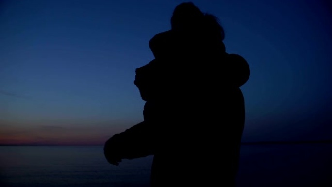 父亲抱女儿的剪影，一起看夜海，团结