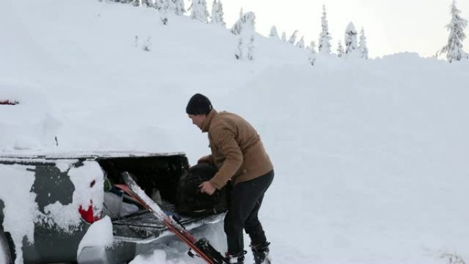 男子从皮卡车上拉滑雪板和行李，暴风雪