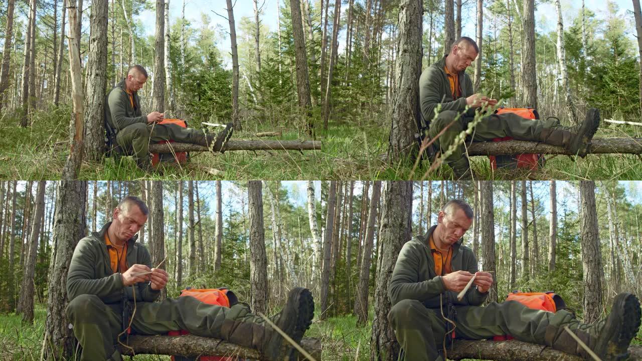 男性荒野生存专家在森林的树干上编织干草