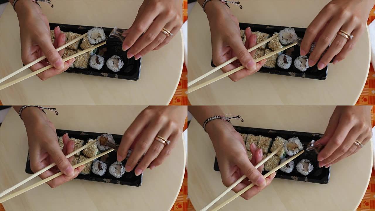 俯视图: 人的手在酱油中蘸寿司