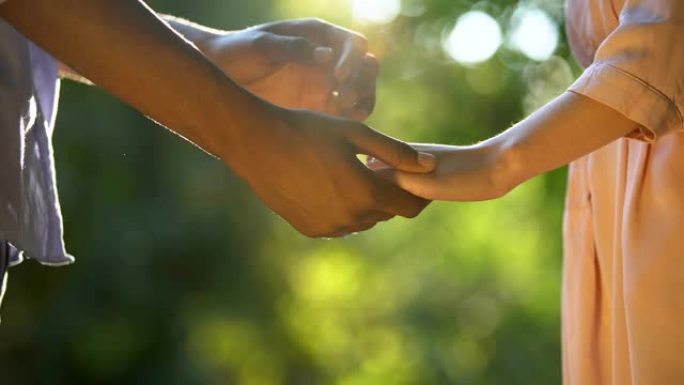非洲裔美国男孩在阳光明媚的公园与女友牵手，信任的关系