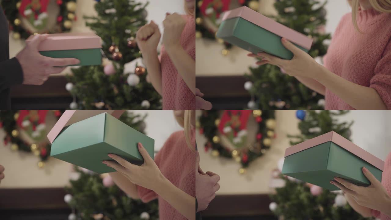 女性高加索人的特写镜头在圣诞树前拿起礼品盒，打开并扔回去。女孩对配偶的新年礼物不满意。关系问题，愤怒