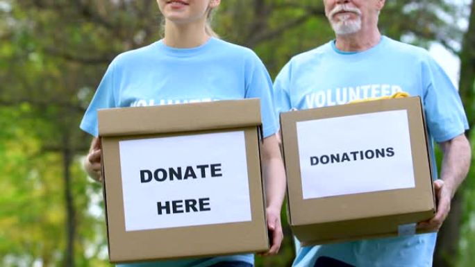 老年和年轻志愿者带着捐款箱走进公园，人道和帮助