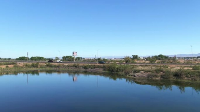 空中无人机在晴朗的蓝天下拍摄了科罗拉多州西部 (大路口) 高速公路旁的一个池塘，上面有一个广告牌