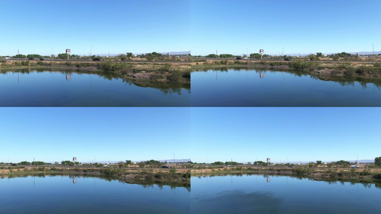 空中无人机在晴朗的蓝天下拍摄了科罗拉多州西部 (大路口) 高速公路旁的一个池塘，上面有一个广告牌