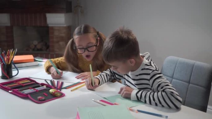 两个白人孩子一起做作业。聪明的兄妹在练习本上写作。穿着条纹夹克的男孩和戴眼镜的女孩坐在家里的桌子旁做