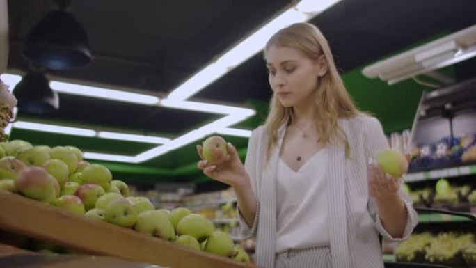 女人在杂货店超市销售中选择新鲜的红苹果，购物市场食品选择带袋子的苹果女孩在购物篮中购买苹果
