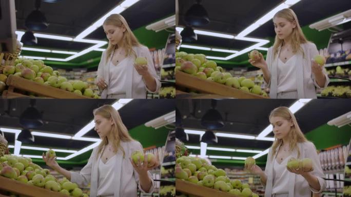 女人在杂货店超市销售中选择新鲜的红苹果，购物市场食品选择带袋子的苹果女孩在购物篮中购买苹果