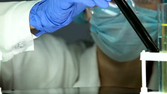 生物化学家在试管中观察油黑液体，在片剂上分型研究结果