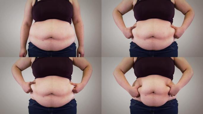 无法辨认的高加索女人肚子的特写。肥胖的成年妇女在肚子上晃动脂肪。超重，肥胖，不健康的生活方式。