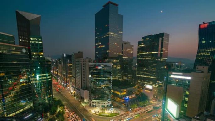 在韩国首尔市汉城江南中心商业区的一个十字路口，光线小径的延时日落场景交通速度加快。