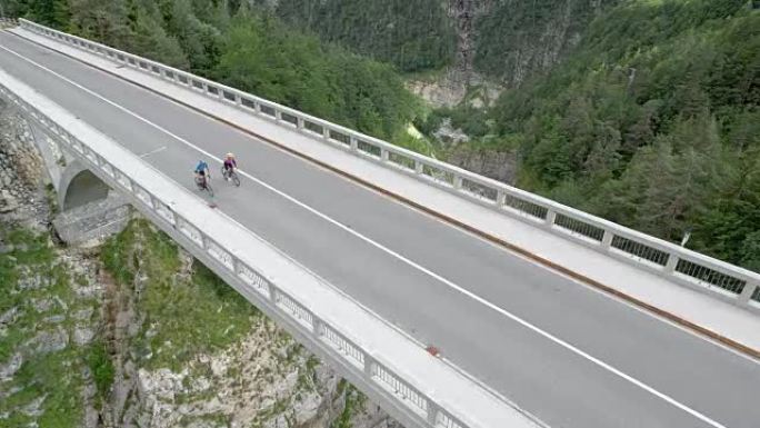 空中两名公路自行车手在山上峡谷上方的一座桥上