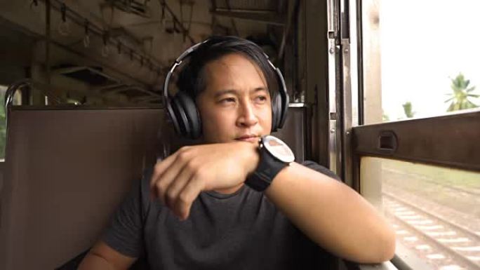 男子坐火车时戴上耳机听音乐