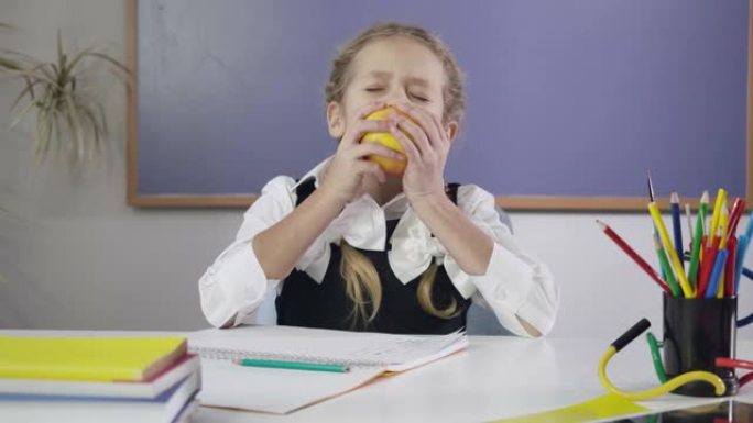 迷人的高加索女学生在练习本上写作，咬苹果，竖起大拇指。做作业的快乐女学生。教育理念，智力。电影院4k