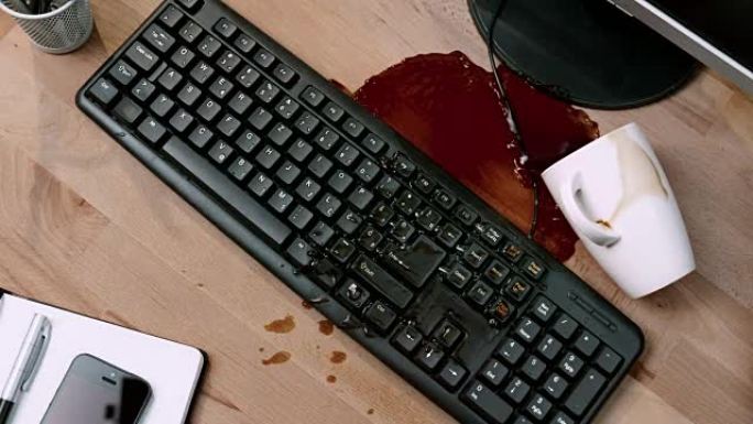 SLO MO LD一杯咖啡被笔记本撞倒，并在办公桌和键盘上拼写
