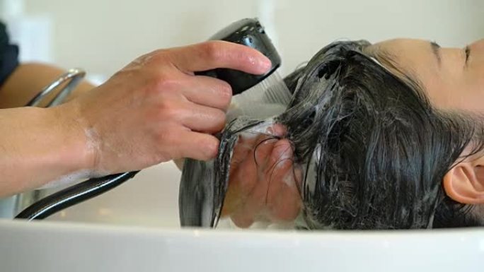 年轻的成年妇女在美发沙龙洗头