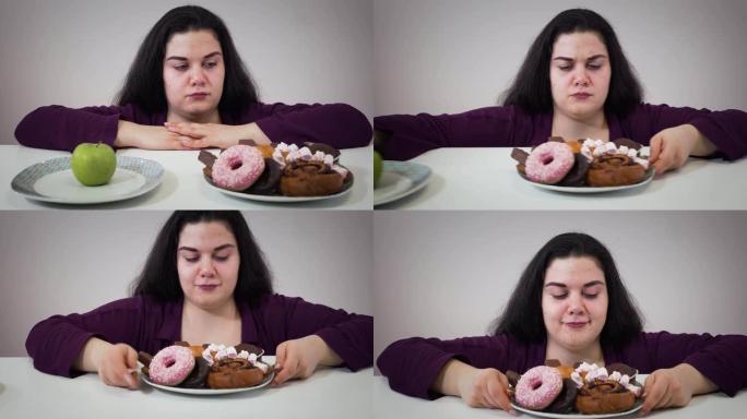 胖胖的白人妇女将苹果放在盘子旁，吃不健康的糖果。有超重问题的微笑丰满女孩的肖像。肥胖，不健康的生活方