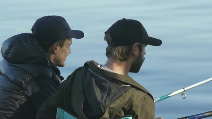 男性朋友聊天享受钓鱼的过程，男性试图钓鱼